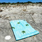 Coastal beach blanket with tassel edges and soft coastal print—your go-to for beach lounging and summer travel.