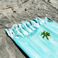Coastal beach blanket with tassel edges and soft coastal print—your go-to for beach lounging and summer travel.
