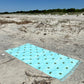 Coastal beach blanket with tassel edges and soft coastal print—your go-to for beach lounging and summer travel.