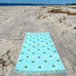 Coastal beach blanket with tassel edges and soft coastal print—your go-to for beach lounging and summer travel.