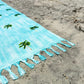 Coastal beach blanket with tassel edges and soft coastal print—your go-to for beach lounging and summer travel.